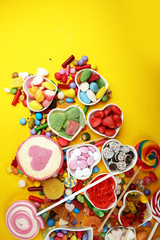 candies with jelly and sugar. colorful array of different childs sweets and treats on yellow background