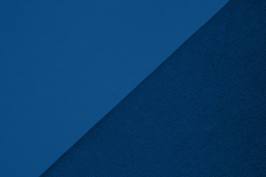 Textured and plain paper sheets divided diagonalliy creating line partition. Classic blue colored abstract duo tone background design. Copy space for text. Top view, flat lay. Color of the year 2020