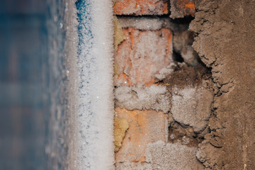 Rime and frost on the wall. Small pieces of ice. Cold in the room.