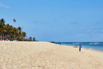 Woman with kite on ocean beach with white sand in sunny day