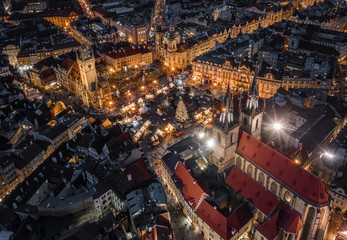 Prague, Czech Republic - Aerial drone view at night of the famous traditional Christmas market with illuminated Church of our Lady Before Tyn, Old Town Hall & Old Town Square at background