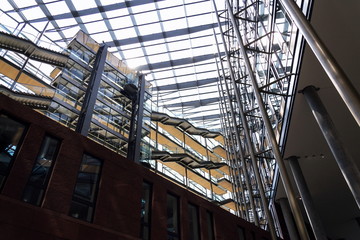 Glass lift at glazed atrium in modern office space interior, future of work, coworking, shared...
