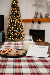 Christmas treats and milk on a plaid table runner with a note for Santa Claus 