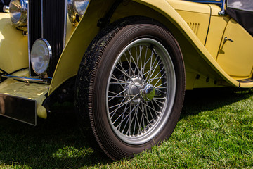 Classic antique car in cream white color on the outdoor grass, the right front wheel view, Vintage...