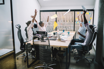 Multiracial adult coworkers celebrating successful deal during meeting in office