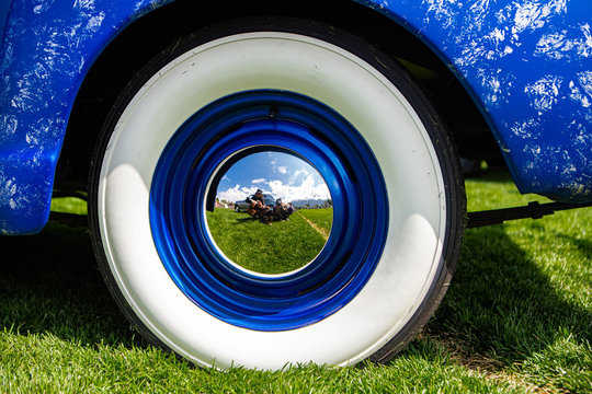 vintage classic American bright blue car wheels on the grass, Close up on the Steel Wheel Chrome center With reflection, and Whitewall tire