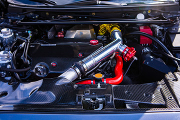 Car under hood showing high performance transverse engine with tuning and modification, red,...