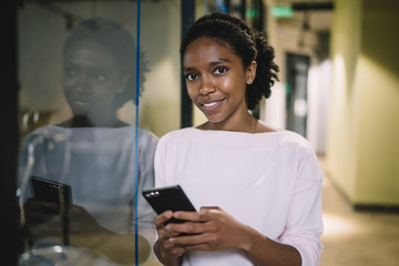 Sensual black lady browsing mobile at workplace