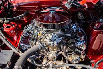 Fototapeta na wymiar red classic muscle car under the hood, v8 engine with big chromed round air intake filter, tubes, wires, pipes, mechanical and electrical other parts
