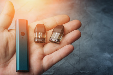 Vape pod system or pod mod with changeable cartridges close up in male hand.