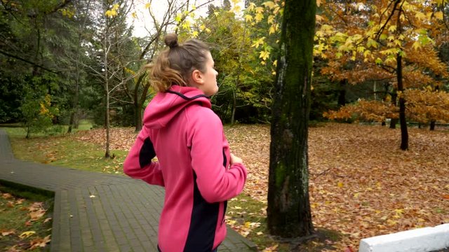 Beautiful woman with long hair jogging in the autumn park. side view