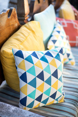 Colorful throw pillow on an cushioned bench