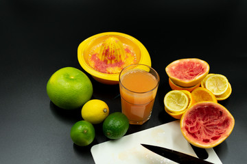 Selbstgemachter Vitaminsaft neben Früchten und benutzter Saftpresse.