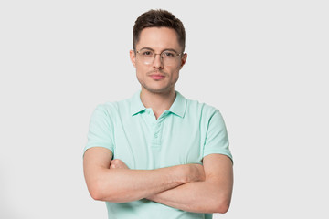Portrait of young man in eyeglasses standing with crossed hands.