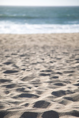Foreground focus on a sandy beach with a shoreline in the background