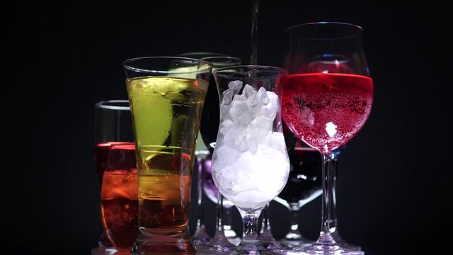 Colourful  cocktails in different shaped glasses and ice. Nightclub party and celebration New Year or Christmas concept. Birthday drinks rotation or spinning on the bar counter.