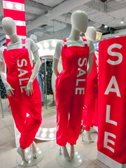 Sale sign red banners and mannequins wearing in red overalls with printed word SALE. Vertical. Black friday, christmas or end of sale season shopping concept.