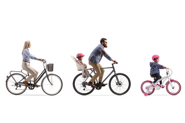 Active family of a mother, father with child in a seat and a little girl riding bicycles