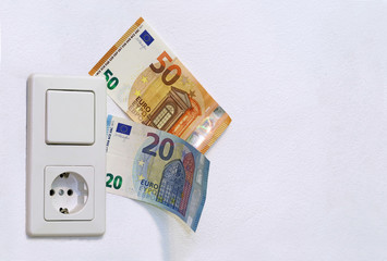 light switch with socket and euro banknotes on white wall, copy space