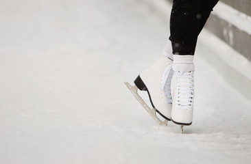 Close up of woman skater legs at open skating rink, bottom view. Female white skates on ice, trains near the wall, learning to balance, copy space.  © DimaBerlin