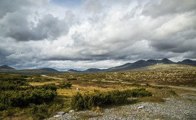 Autumn in Rondane National Park, mountain range and dark, cloudy sky, Norway.