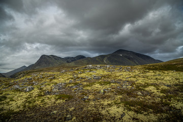 Autumn in Rondane National Park, mountain range and dark, cloudy sky, Norway.