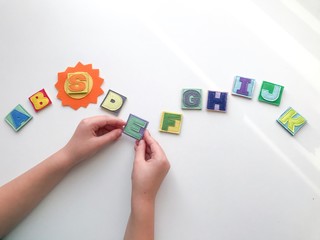Learning the alphabet with a child. Hands hold letters. Learn by playing.