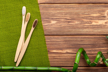 Bamboo toothbrushes, bamboo plant on wooden background. Flat lay copy space. Natural bath products. Biodegradable natural bamboo toothbrush. Eco friendly, Zero waste, Dental care Plastic free concept