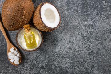 Fototapeta na wymiar Glass bottle of coconut oil with fresh coconut fruit on rustic background, alternative theraphy medicine concept, Cocos nucifera
