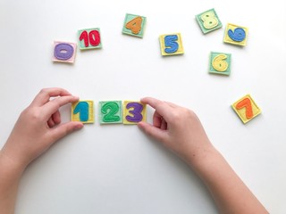 Learning numbers with a child. Hands holding numbers. Learn by playing.