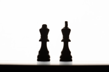 Chess pieces on a board. Backlit with a white background.