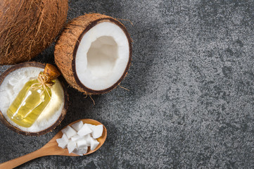 Glass bottle of coconut oil with fresh coconut fruit on rustic background, alternative theraphy medicine concept, Cocos nucifera