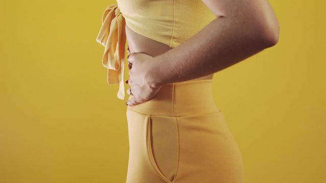 Woman suffering stomach ache and complaining. Menstrual cramps. Young beautiful woman is having stomach ache. On yellow background. 4K.