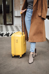 Close up casual girl in coat standing with suitcase outdoor