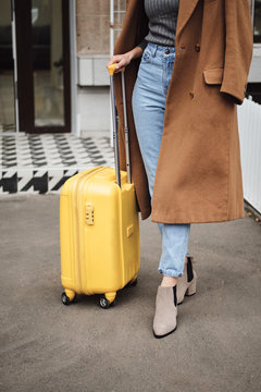 Close up casual girl in coat standing with suitcase outdoor