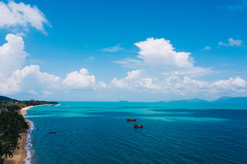 Aerial scenery view of white sand beach shore with turquoise clear sea water and foamy waves. Bird's eye panoramic view of picturesque coastline bay with fishermen boats. Samui island, Thailand