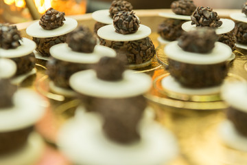 Close-up of chocolate candy adorning the cake table at wedding party. Chocolate and ostia jam on a golden tray. Religious party concept. Selective focus. Wedding party decoration.
