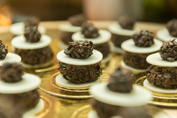 Close-up of chocolate candy adorning the cake table at wedding party. Chocolate and ostia jam on a golden tray. Religious party concept. Selective focus. Wedding party decoration.