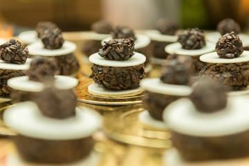 Close-up of chocolate candy adorning the cake table at wedding party. Chocolate and ostia jam on a golden tray. Religious party concept. Selective focus. Wedding party decoration.