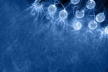 Christmas fir branch with decorative garlands balls glowing light toned in blue color