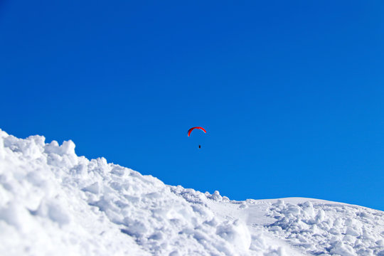 paraplane flying over snowy Caucasus mountains sunny blue sky