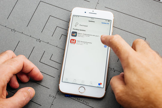 PARIS, FRANCE - SEP 26, 2016: Male hand holding New Apple iPhone 7 8 Plus smartphone after unboxing and testing by installing the app application software HSBC DEEZER Online banking apps purchased