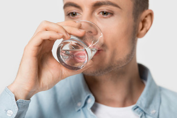 Close up young healthy thirsty guy drinking water.