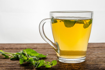 Cup of herbal tea with fresh mint on wooden