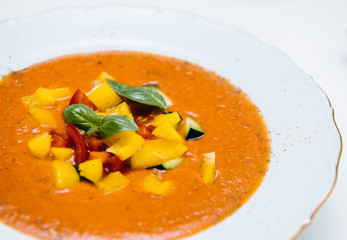 Side view of delicious homemade gazpacho in white bowl on a white table made from organic bio ingredients