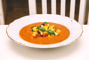 Front view of delicious homemade gazpacho in white bowl on a white table made from organic bio ingredients