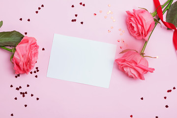 Empty greeting card on the pink table with roses nd small heart shaped confetti
