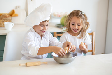 Obraz na płótnie Canvas children in white chef uniform preparing food on the kitchen