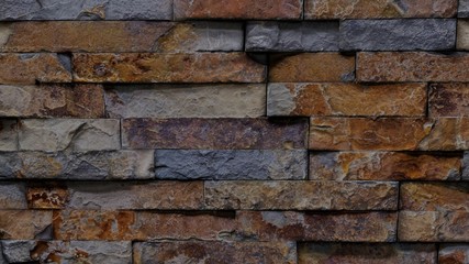 Background texture image of outdoor wall covered with rough shaped bricks.