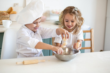 Obraz na płótnie Canvas Family kids in white chef uniform preparing food on the kitchen